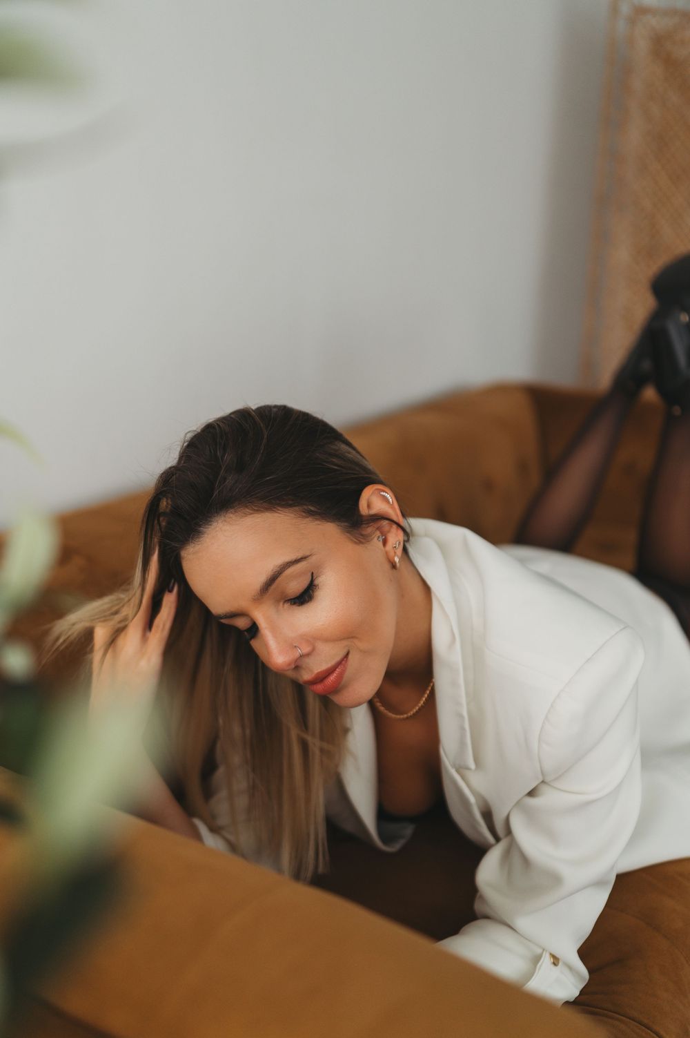 Soft portrait of someone in white blazer leaning forward with natural lighting.