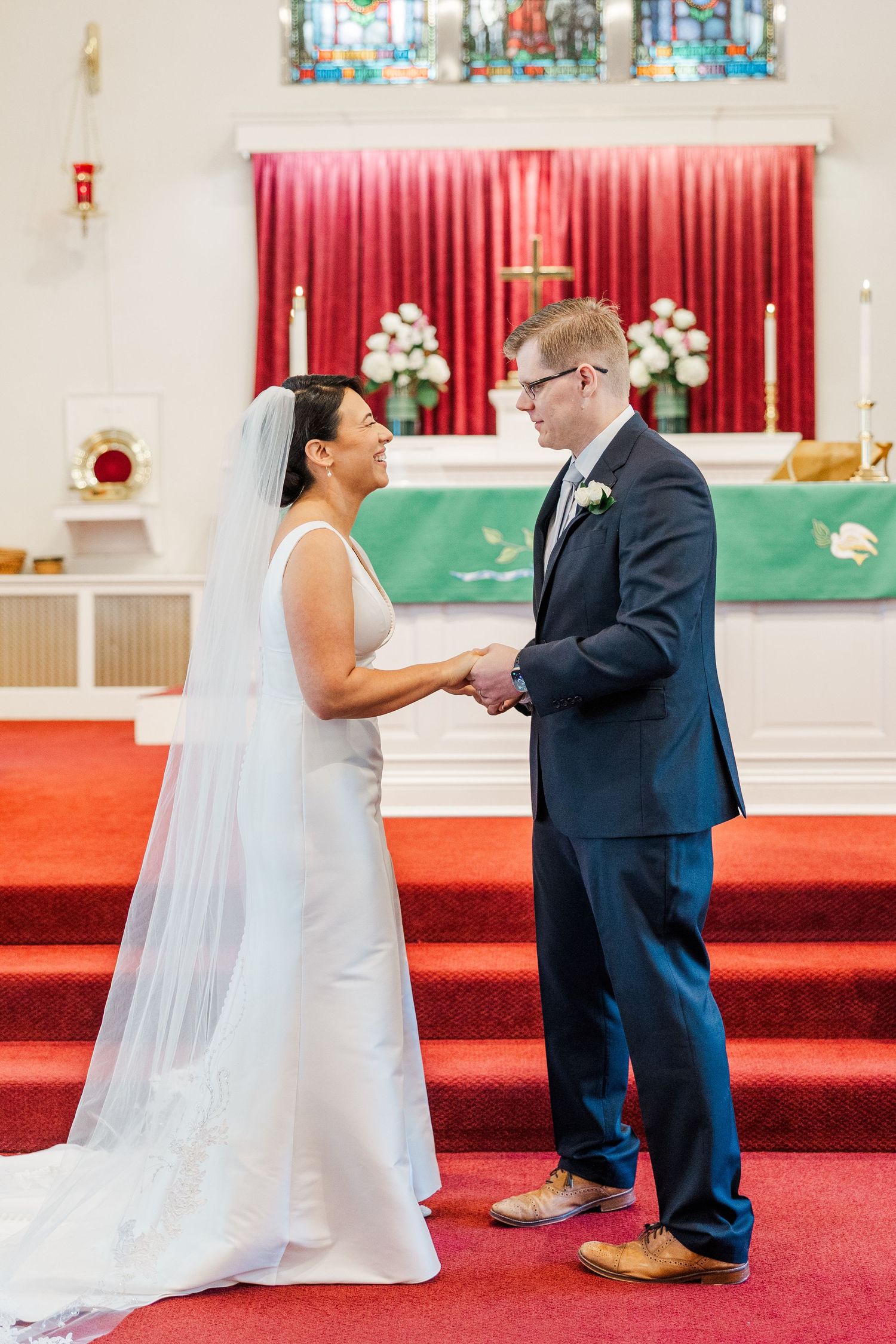 Wedding ceremony moments captured inside a church with red carpet and stained glass windows.