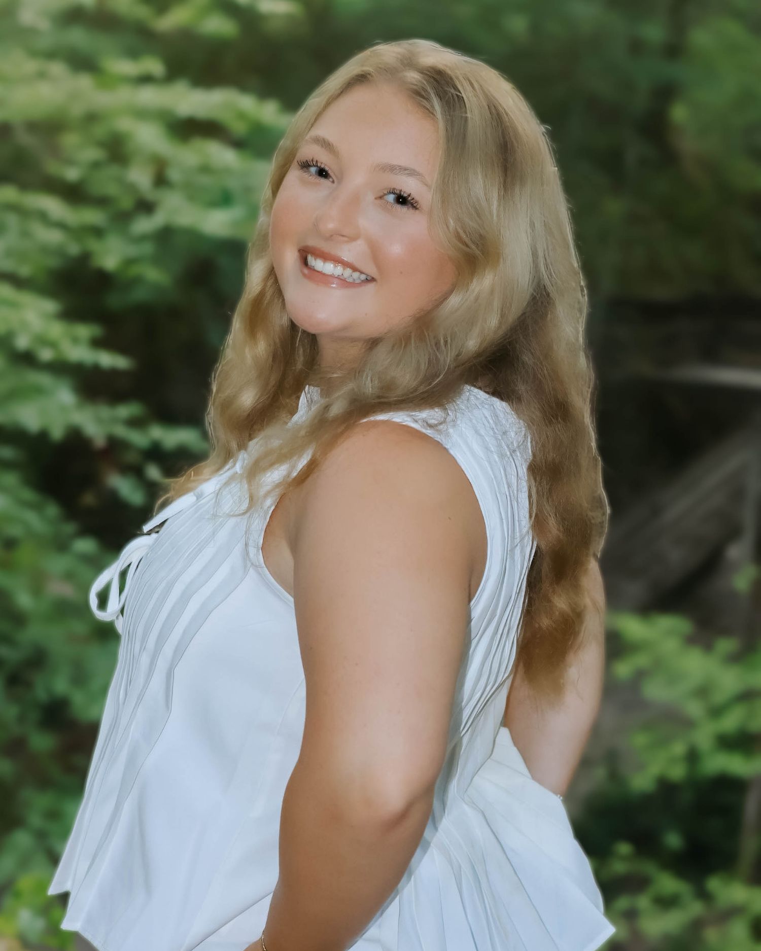 Summer portrait series with flowing white top against green foliage.