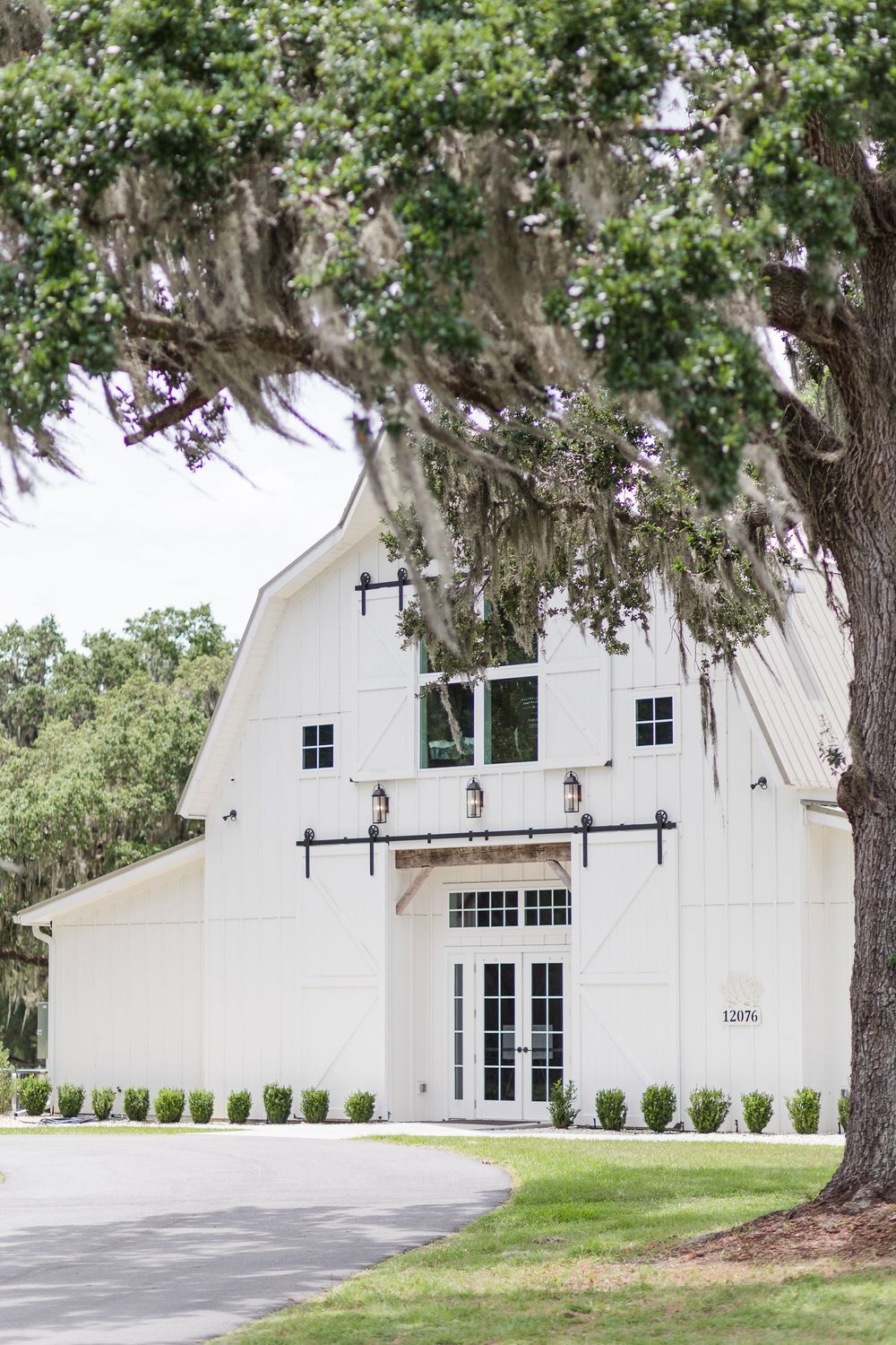 Modern white barn wedding venue with French doors and Spanish moss draped oak trees.