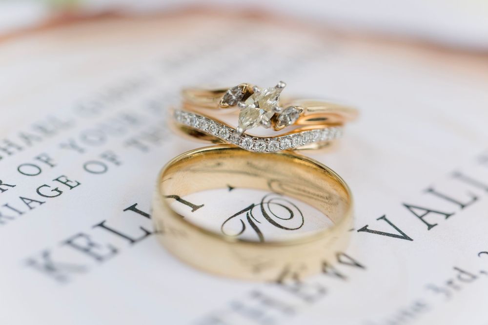 Gold wedding rings with diamonds rest on white paper with text, showing elegant wedding jewelry details.