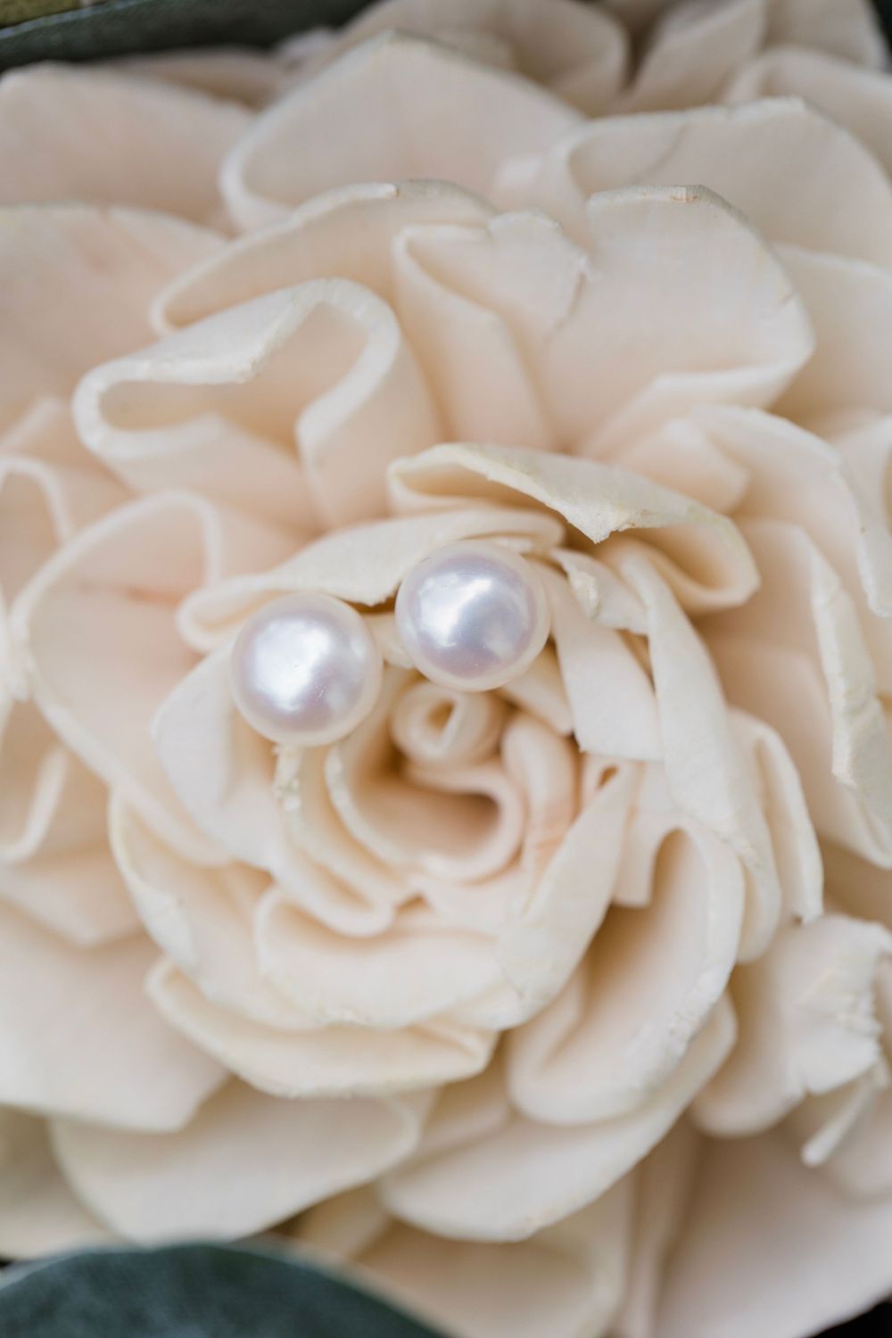Delicate cream-colored fabric roses adorned with pearl centers create an elegant floral arrangement.