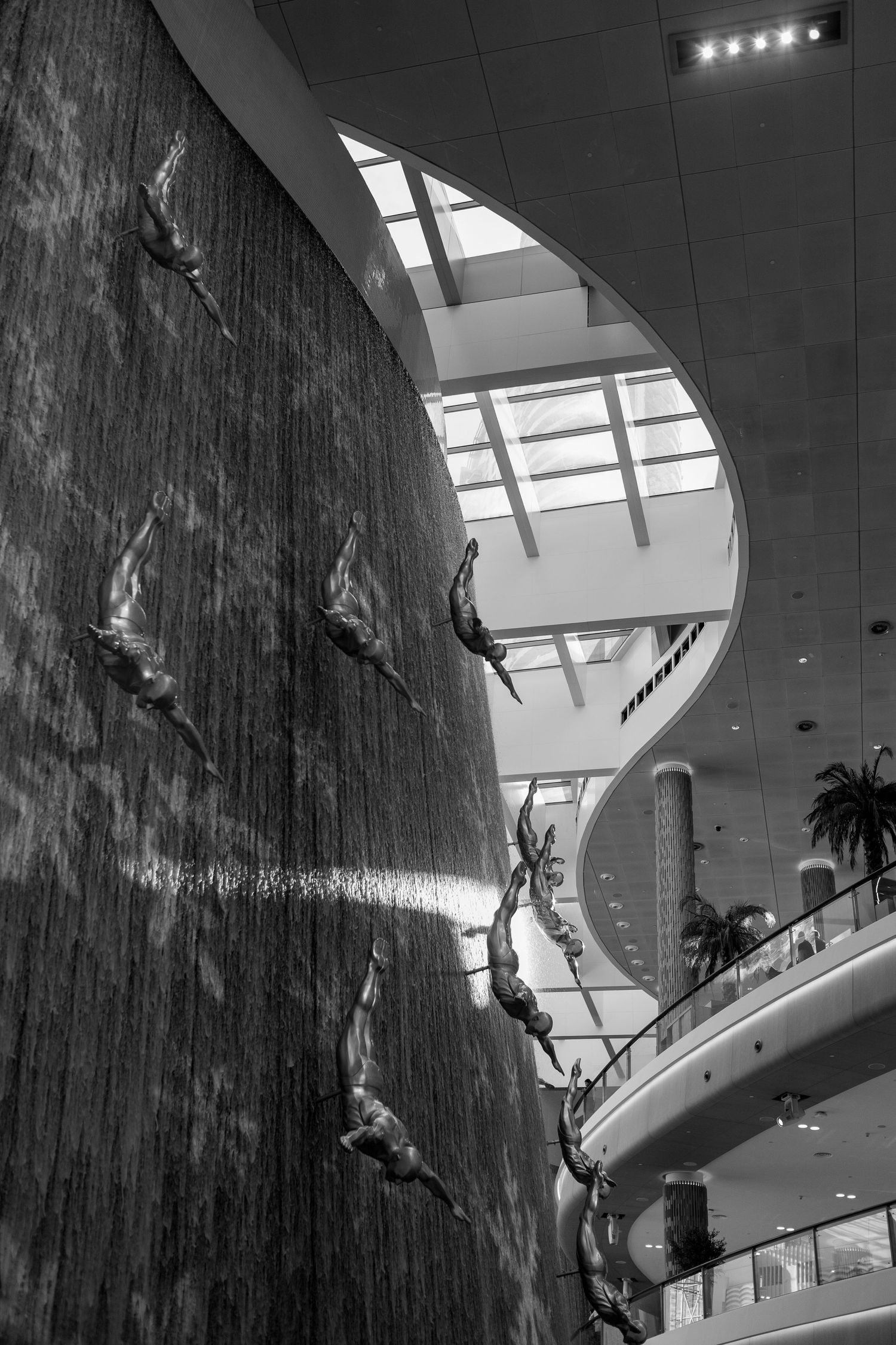 Indoor rock climbing wall with multiple climbers scaling a steep artificial surface in a modern facility.