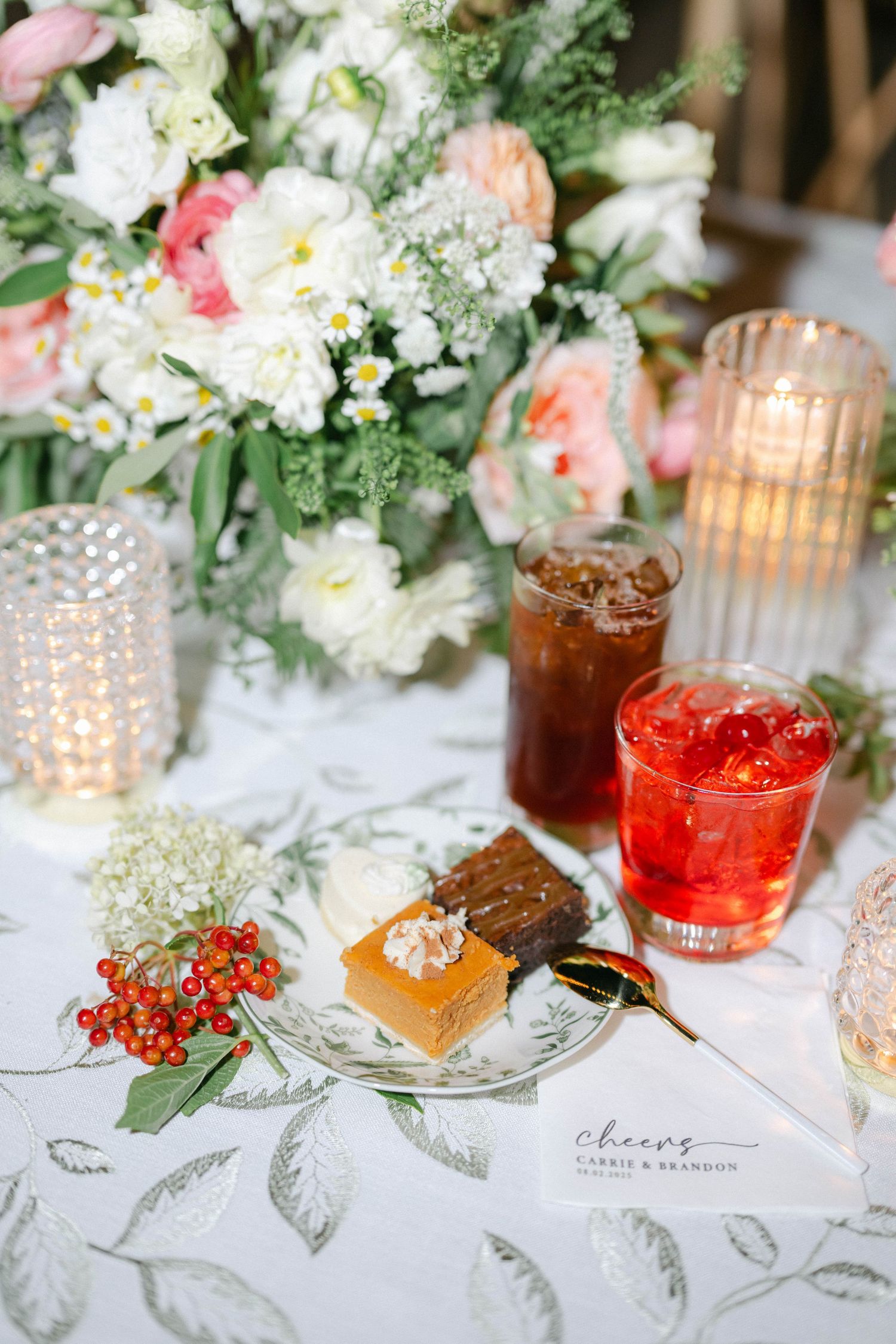 Elegant table setting with floral centerpiece, cocktails, and desserts on a leaf-patterned tablecloth with glowing candles. - Elawa Farm