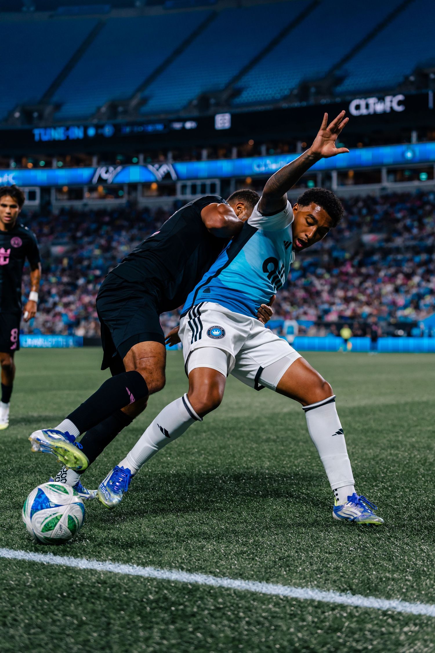 Two Charlotte FC soccer players battle for the ball during an MLS match at Bank of America Stadium.