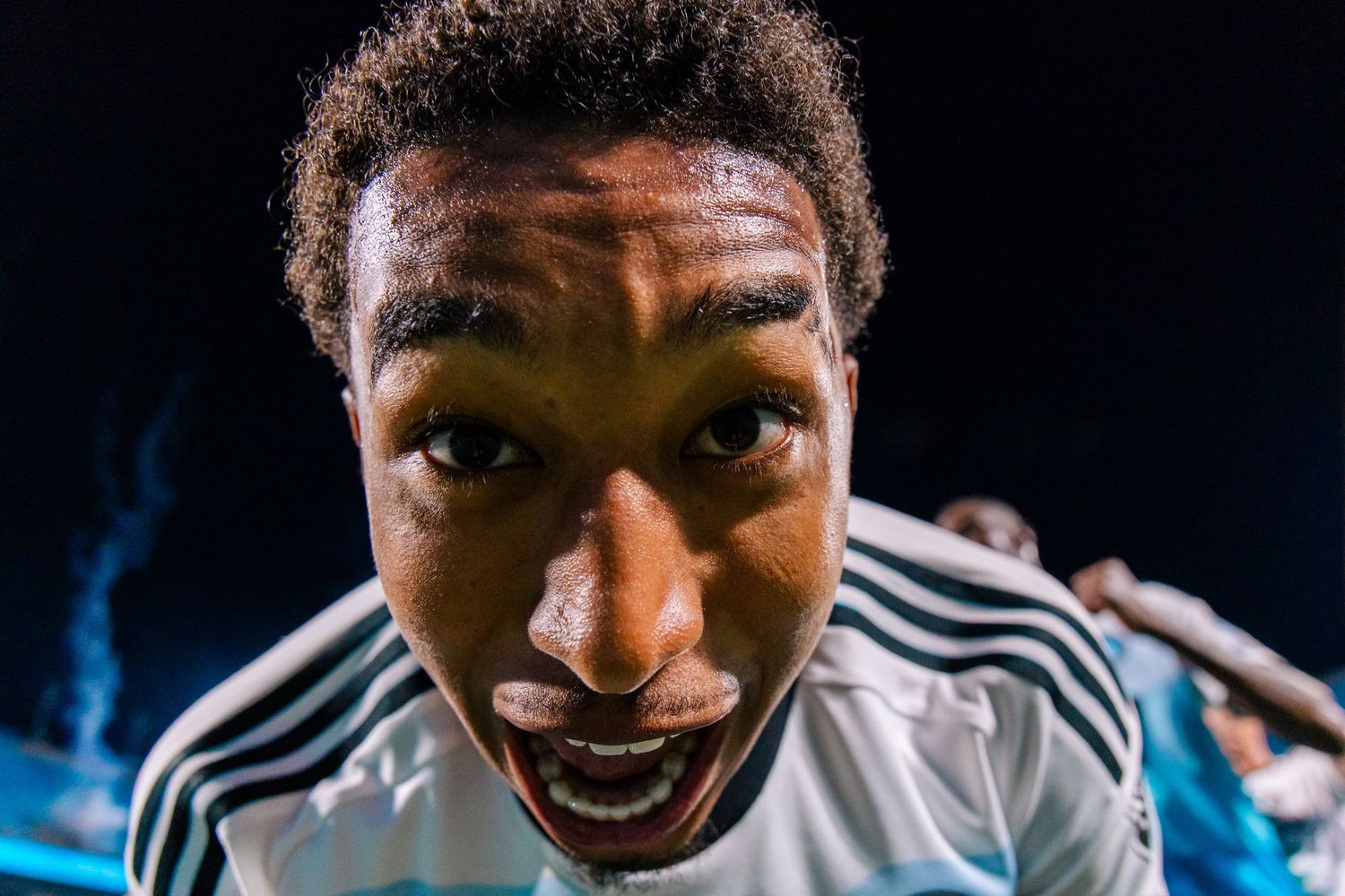 Close-up fisheye portrait of a sweaty soccer player with an expressive open-mouthed look on his face.