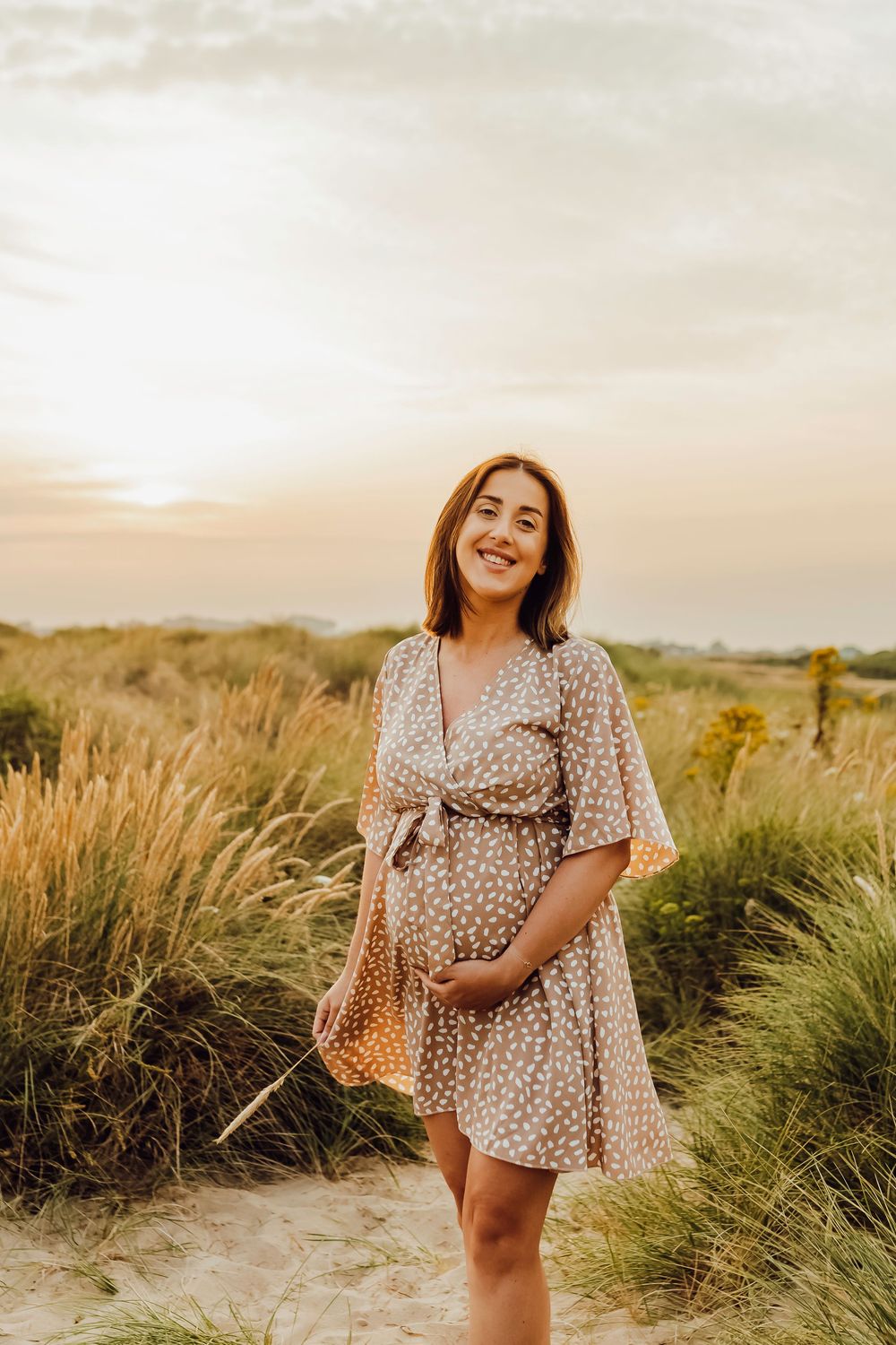 Pregnant woman photographed near tall beach grass during golden hour at Southbourne Beach, Dorset