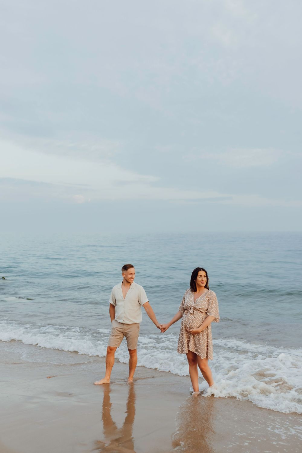 Maternity couple standing together in the sea at sunset on Southbourne Beach, Dorset, natural and romantic photography