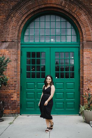A sequence of photos showing a black dress against emerald green garage doors on a brick building exterior.