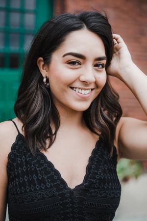 Portrait series against a green and brick background showcasing a black crochet dress.