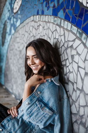 Creative portrait series with mosaic wall background featuring denim jacket and natural lighting effects.