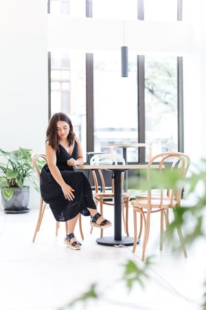 Modern indoor lifestyle photoshoot in bright minimalist space with wooden chairs and plants.