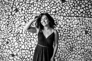 A black and white photo series shows a figure posing against a mosaic tiled wall in different artistic poses.