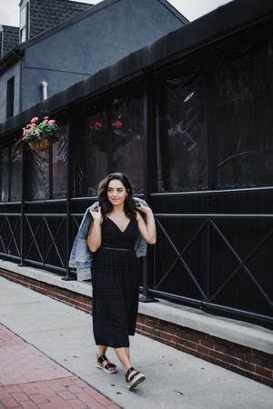 A series of four fashion portraits showing a woman in a black dress posing against a dark urban backdrop.