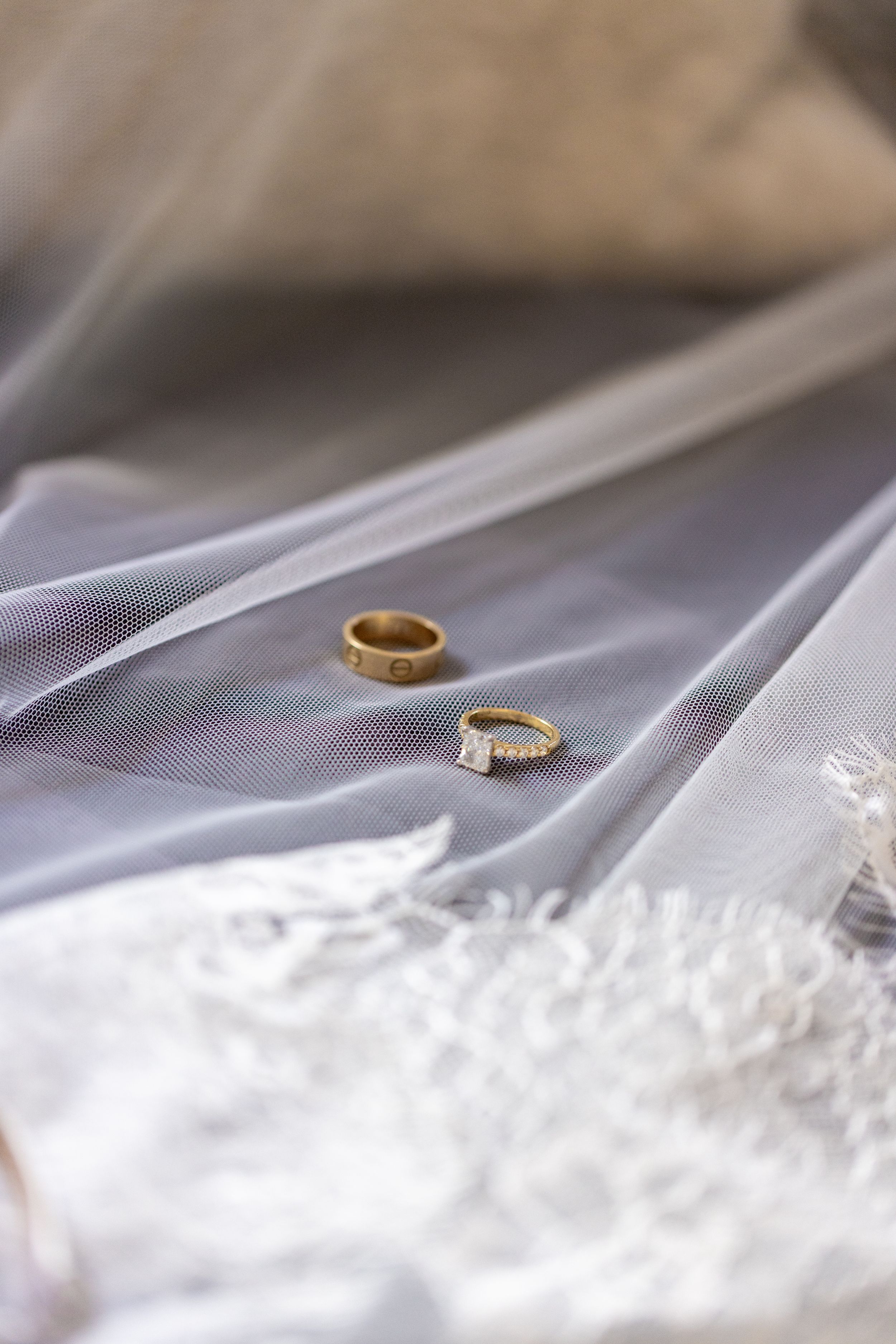 Wedding rings resting on delicate white lace fabric with soft focus.