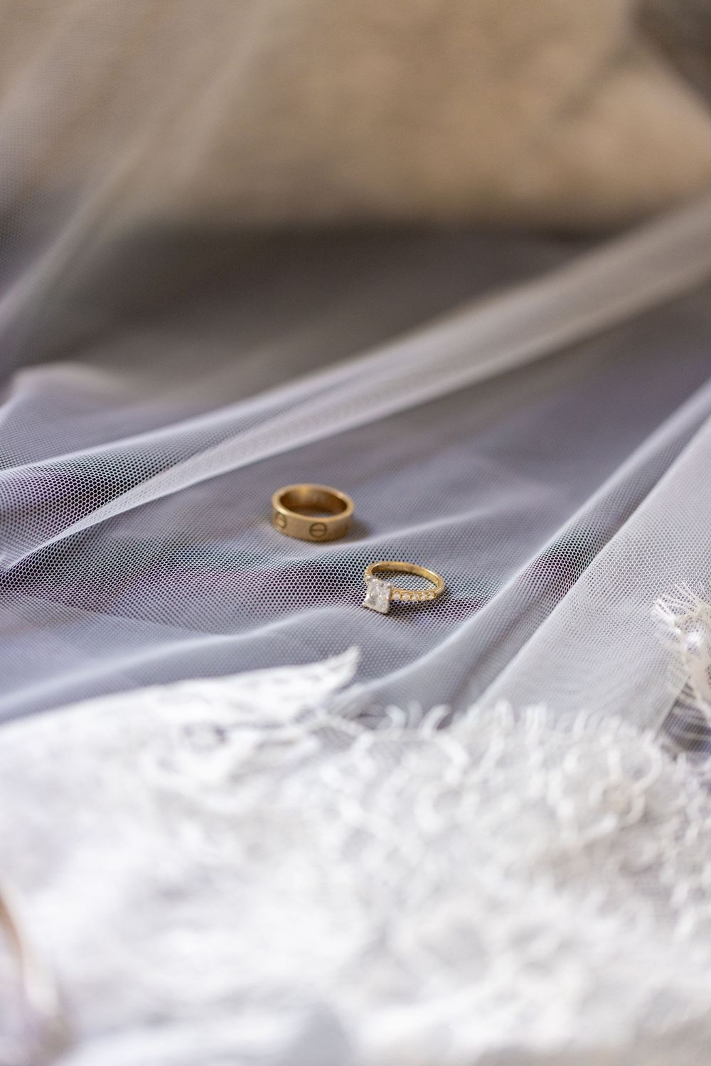 Wedding rings resting on delicate white lace fabric with soft focus.