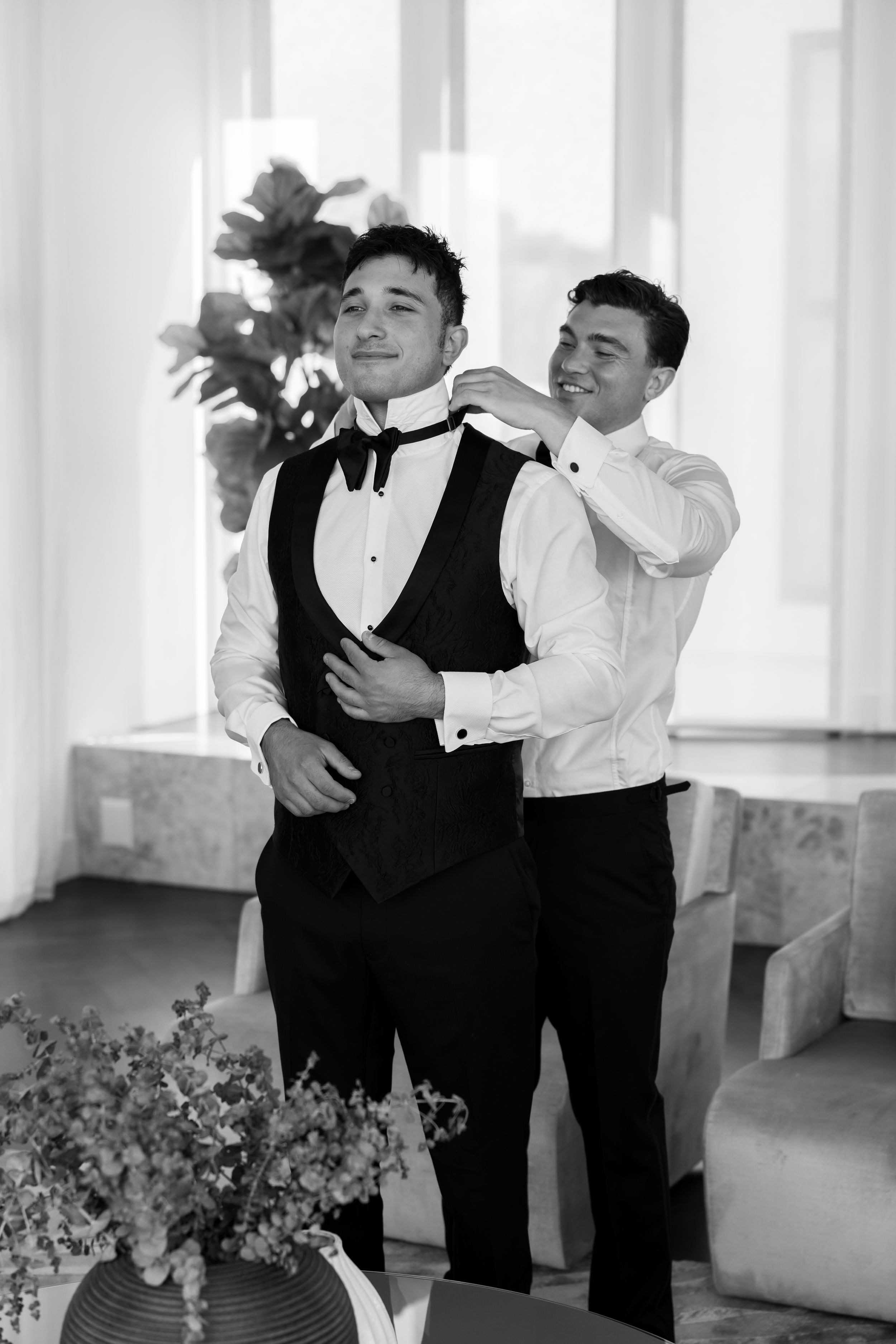 Two people in formal attire share a playful moment in bright indoor venue.