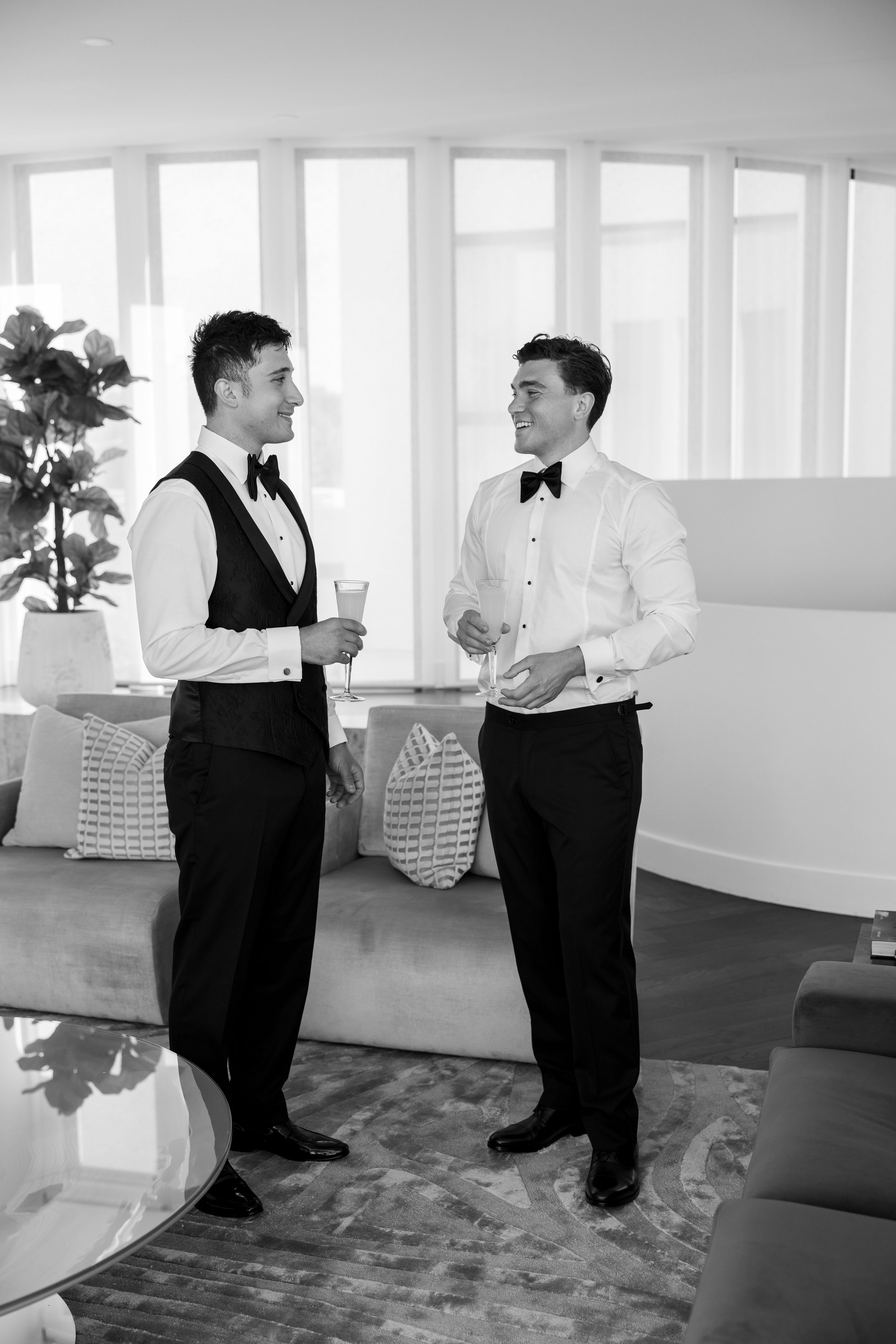 Two people in formal wear having animated conversation in bright indoor space.