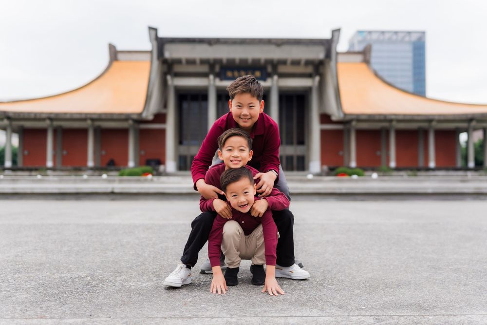 Children play and pose together in a traditional Asian courtyard with temple architecture in the background.
