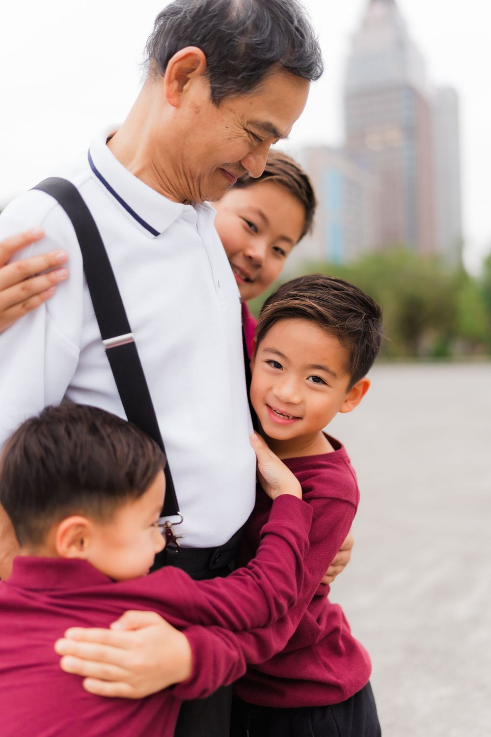 A joyful candid moment showing affectionate embraces in burgundy and white against an urban backdrop.