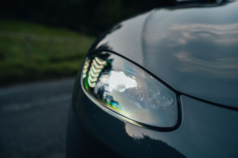 Black automotive surface with reflective finish shown in dramatic lighting.