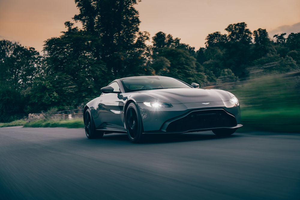 Luxury sports cars parked in a row at sunset with trees in the background.