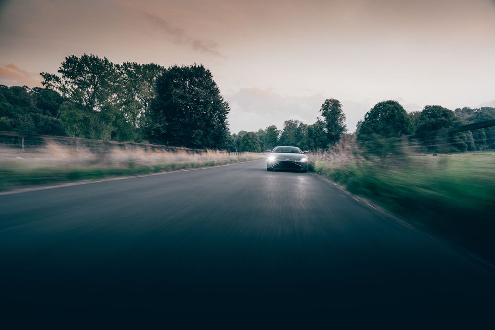 Moody foggy road at dusk with car headlights illuminating through misty atmospheric conditions.
