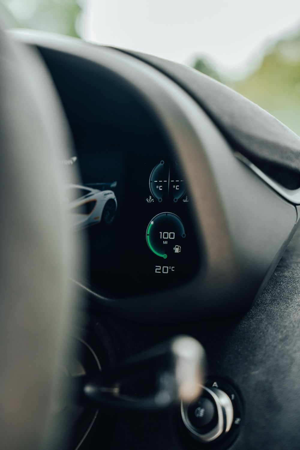 Close-up view of a modern digital car dashboard display showing speed at 100 with a green circular gauge.