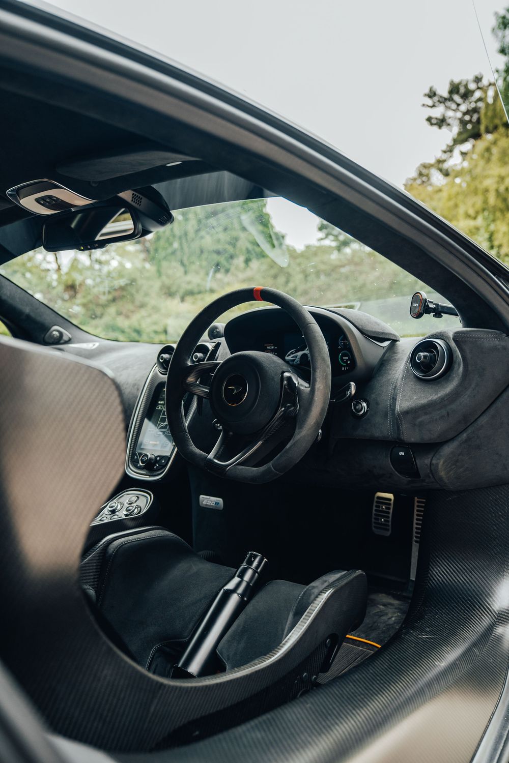 Interior view of a McLaren sports car showing the steering wheel, dashboard and carbon fiber details in modern design.
