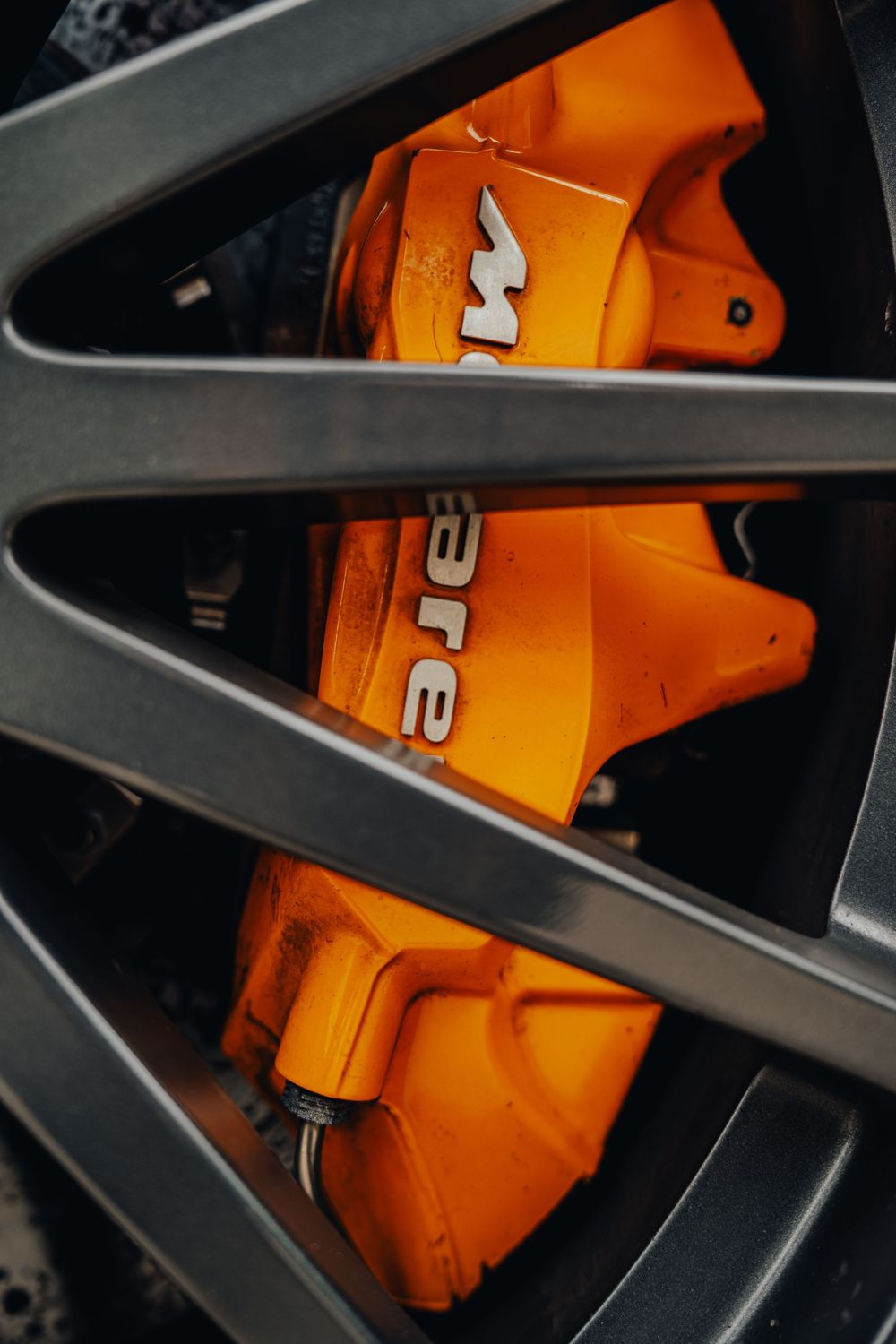 Close-up view of orange bicycle wheel spokes intersecting with black metal frame creating geometric patterns.