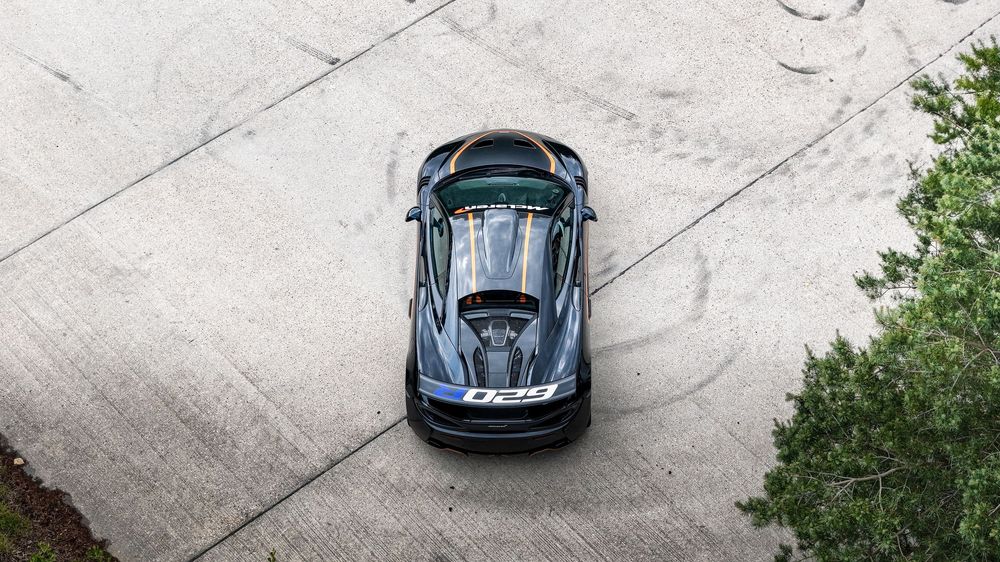 Aerial shots of a black McLaren P1 parked on a concrete surface with green landscaping visible.