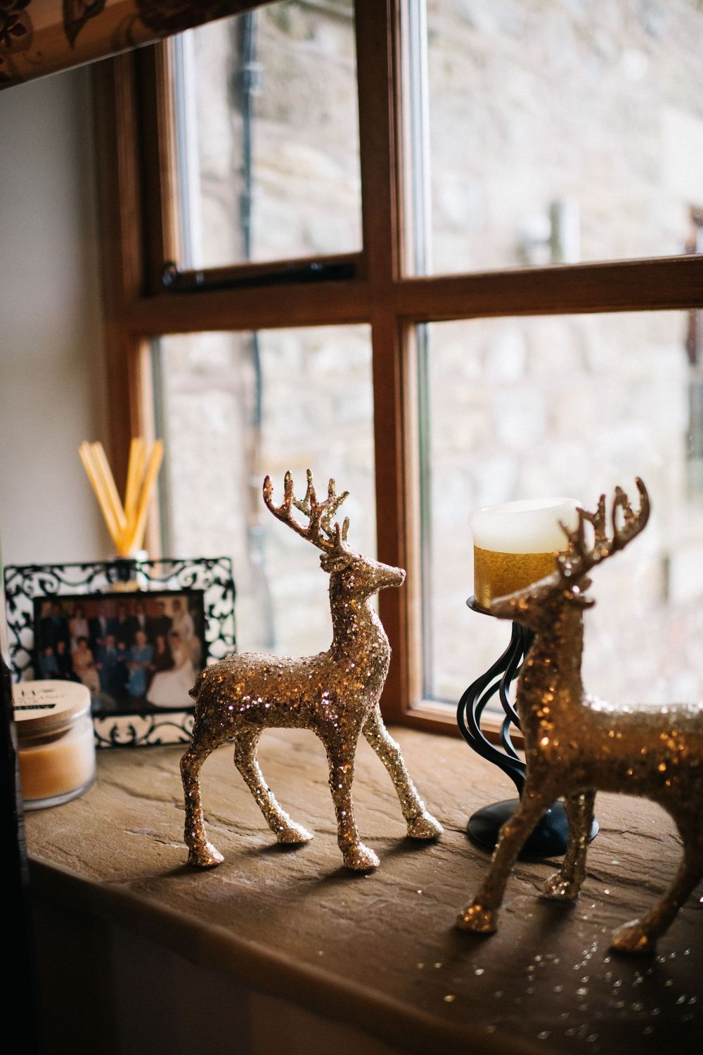 Decorative golden reindeer figurines arranged on a wooden windowsill create a festive holiday display.