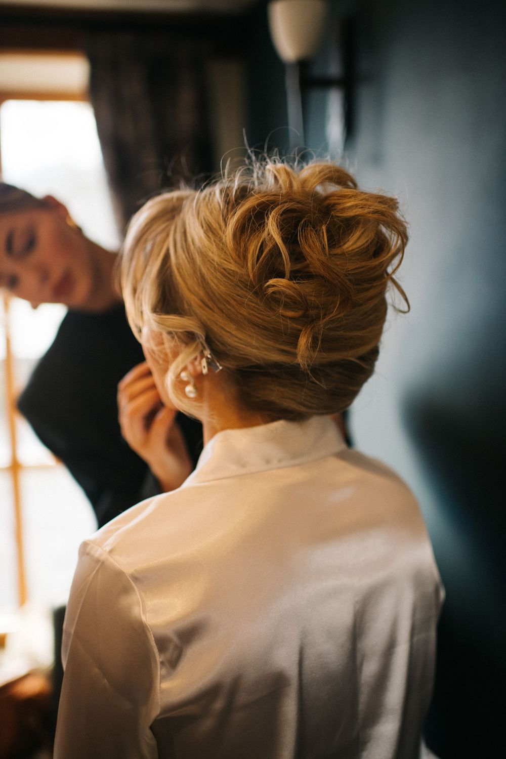 Close-up view of someone getting their hair styled in an elegant updo for a formal event.