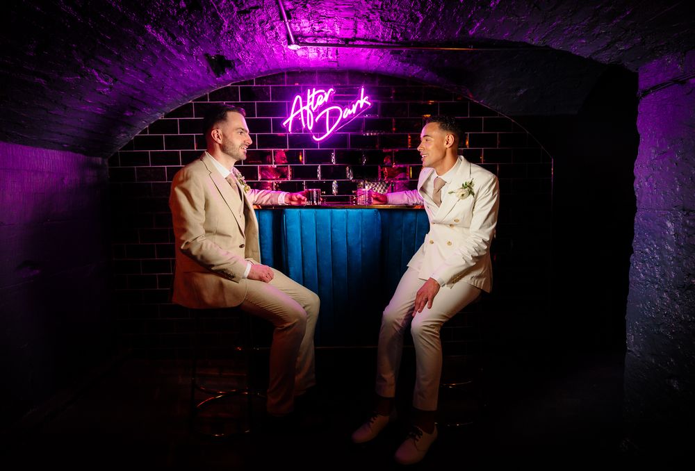 Underground lounge area with pink neon signs and dramatic mood lighting. Ellingham Hall