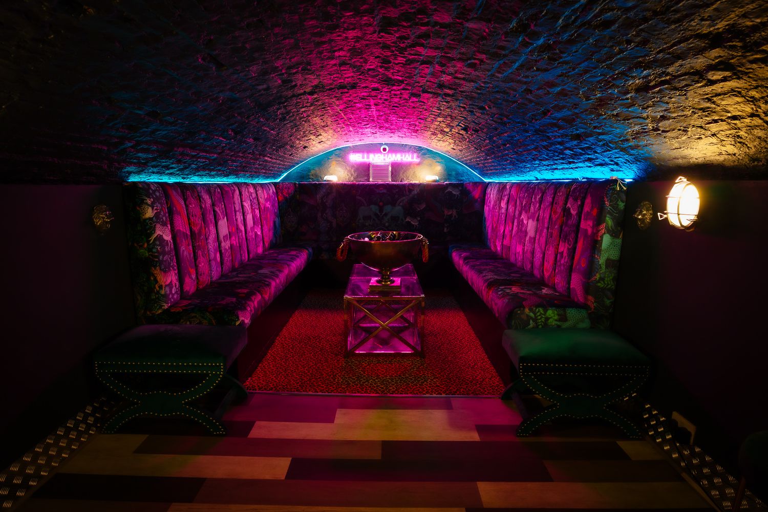 Brick archway venue space illuminated by dramatic pink and blue lighting effects. Ellingham Hall