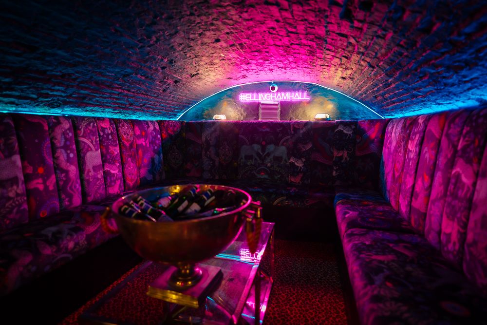 Underground venue illuminated with vibrant pink and blue lighting creating a dramatic atmosphere. Ellingham Hall