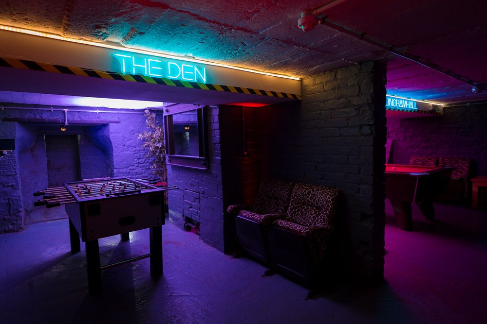 Underground entertainment space with blue neon signage and exposed brick walls. Ellingham Hall