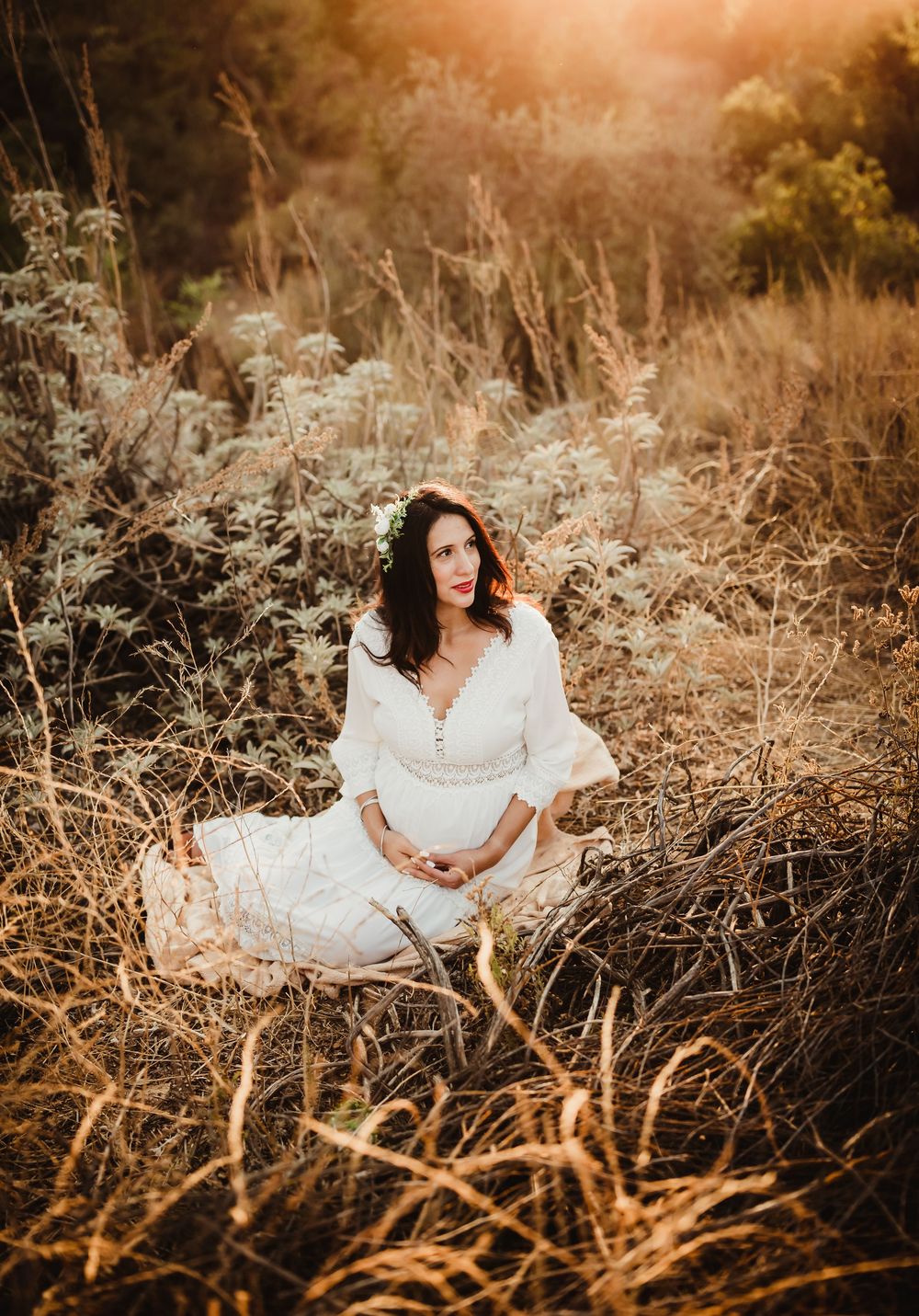 A person in a white dress poses gracefully in a golden autumn field at sunset, creating a dreamy outdoor portrait series.