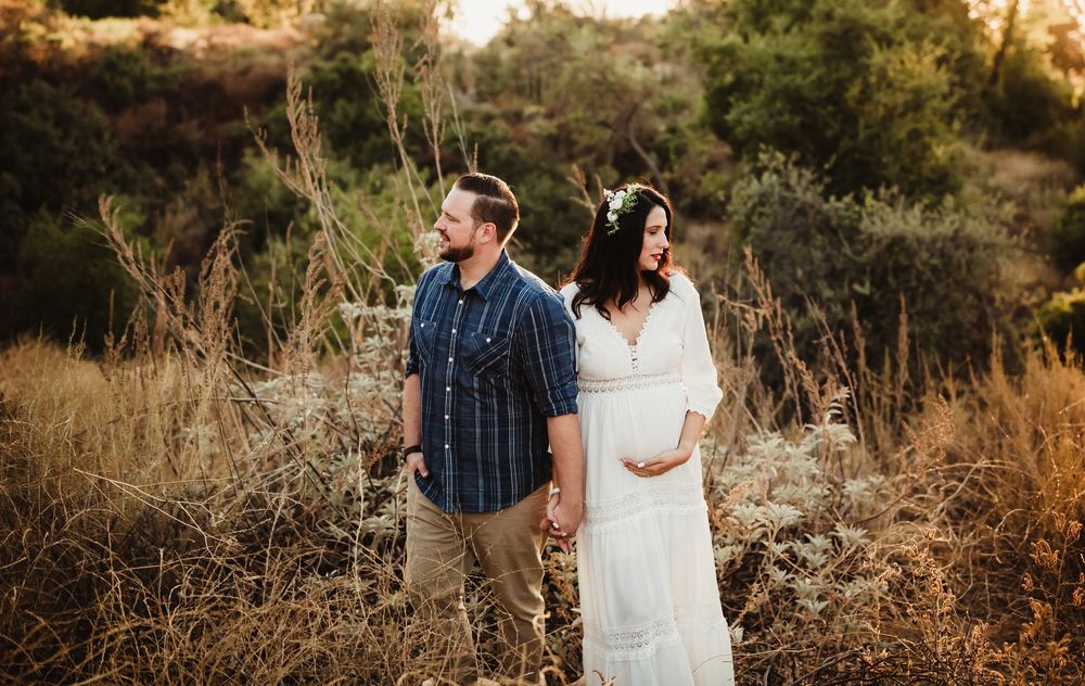 A couple shares an intimate moment in a golden field at sunset during their engagement photo session.