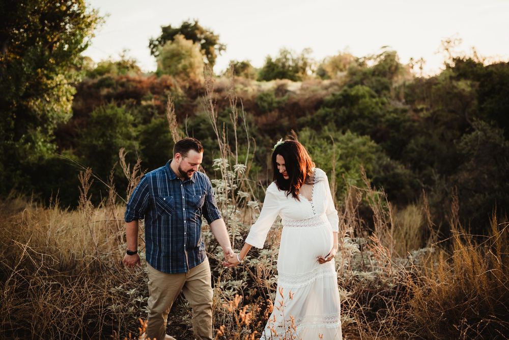 A couple shares a tender moment together in a golden field during sunset.