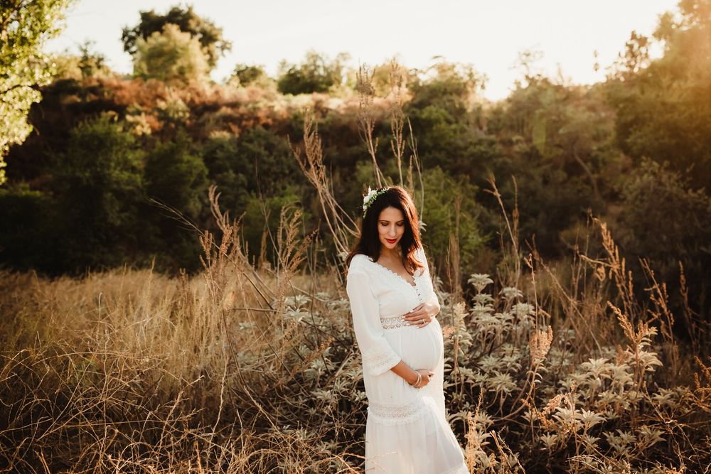 A series of romantic sunset maternity photos taken in a golden-lit field with tall grass and natural scenery.