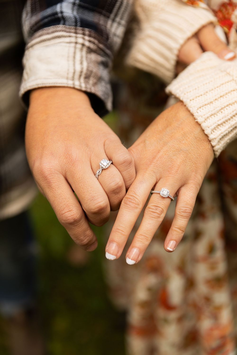 Close-up of couple's hands displaying sparkling diamond engagement rings during fall engagement session.