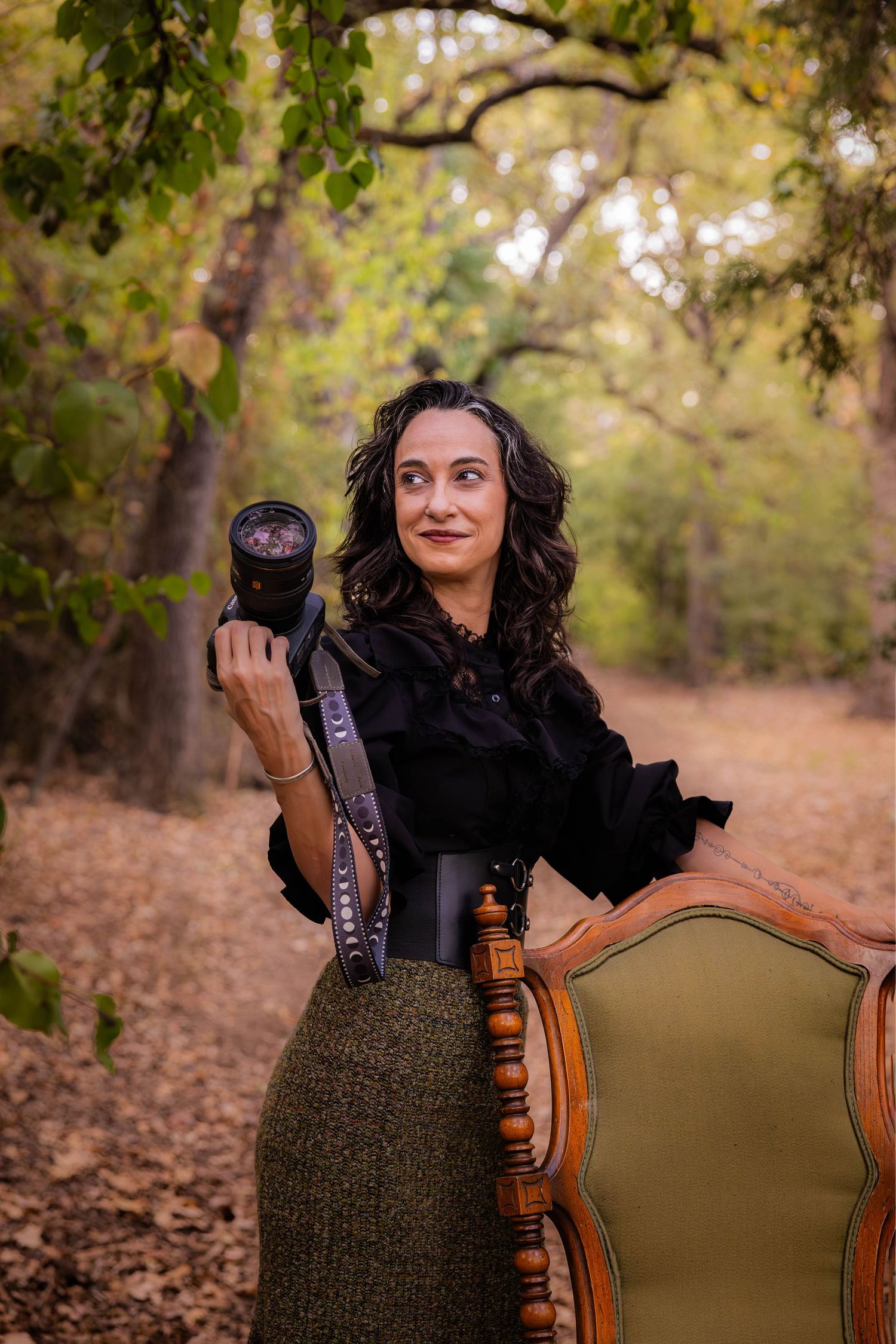 A woman poses holding her camera.