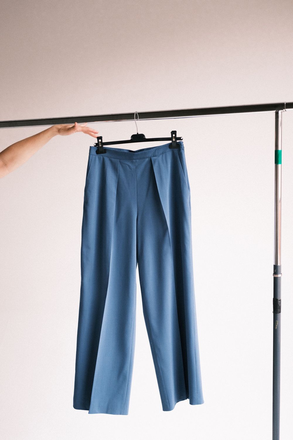 A sequence of photos showing blue trousers hanging on a clothing rack from different angles.