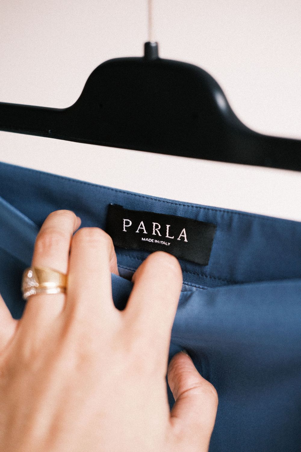 Close-up view of hands holding a navy blue Farla brand clothing tag.