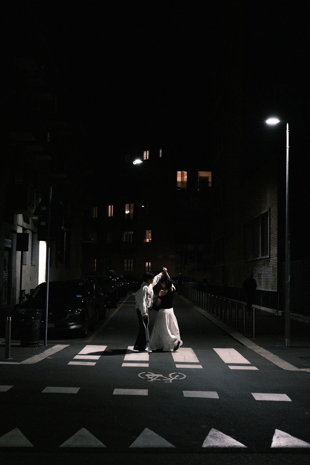 A sequence of four nighttime photos shows a person in white crossing an illuminated crosswalk on a dark street.