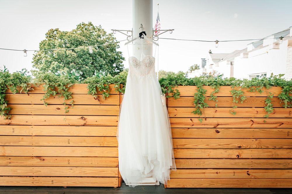 Elegant bridal gown displayed against rustic wooden wall panels with climbing vines.