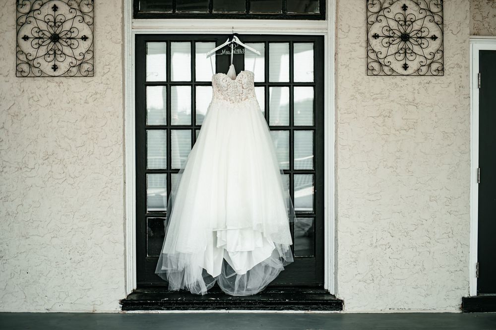 White wedding gown displayed against architectural windows with decorative details.