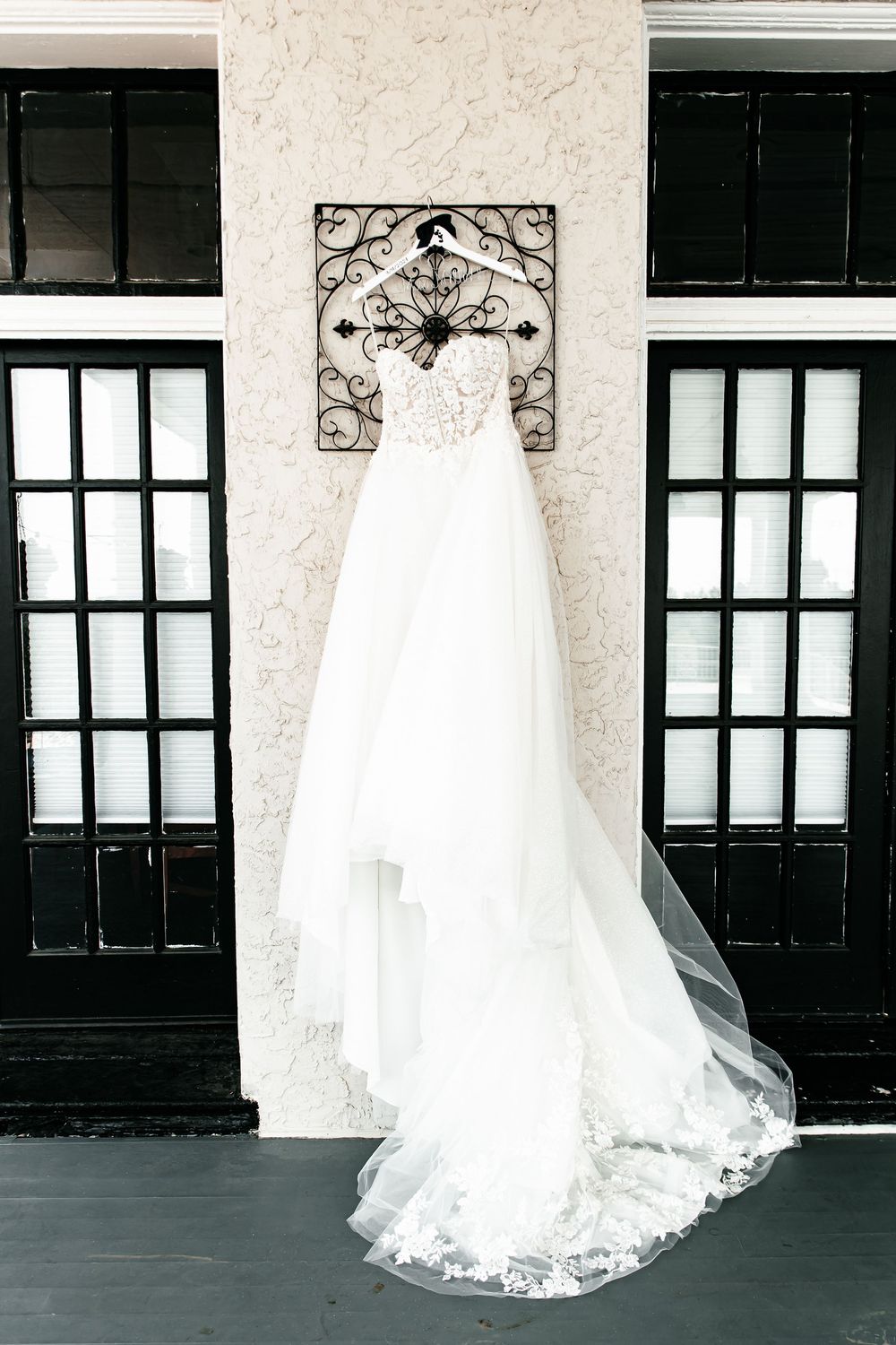 Wedding gown with flowing train displayed against black and white architectural elements.