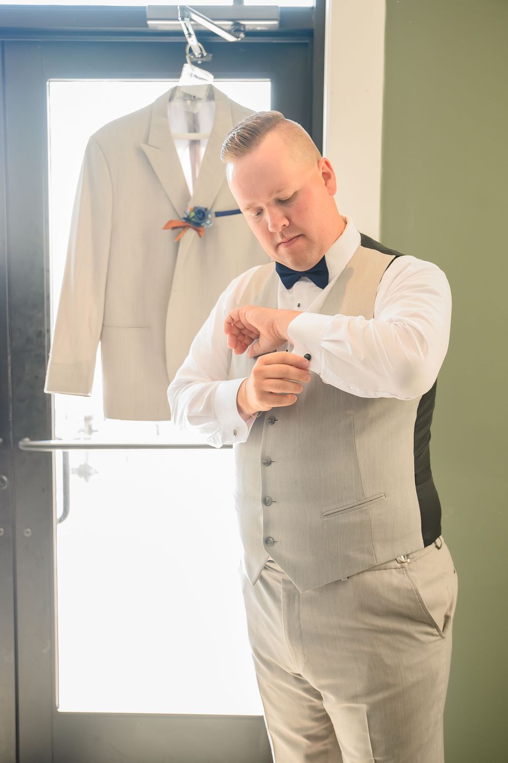 Someone in formal attire checks their appearance while getting ready in a dressing room.